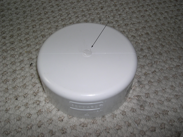 Photograph of large pipe cap, with arrow indicating central projecting mold mark to be removed.