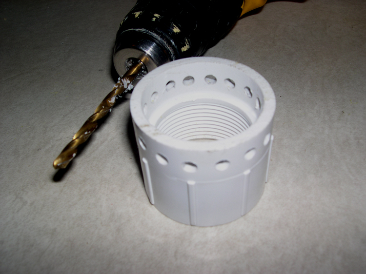 Photograph of coupling after drilling, with drill, showing placement of holes around freshly-cut rim.