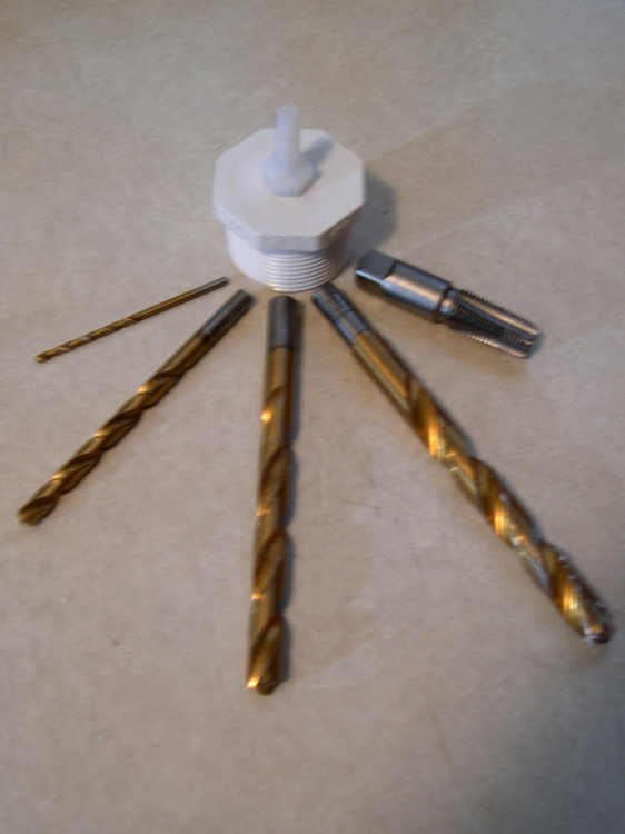 Threaded plug with hose barb installed, showing series of drills and tap used to produce threaded hole.